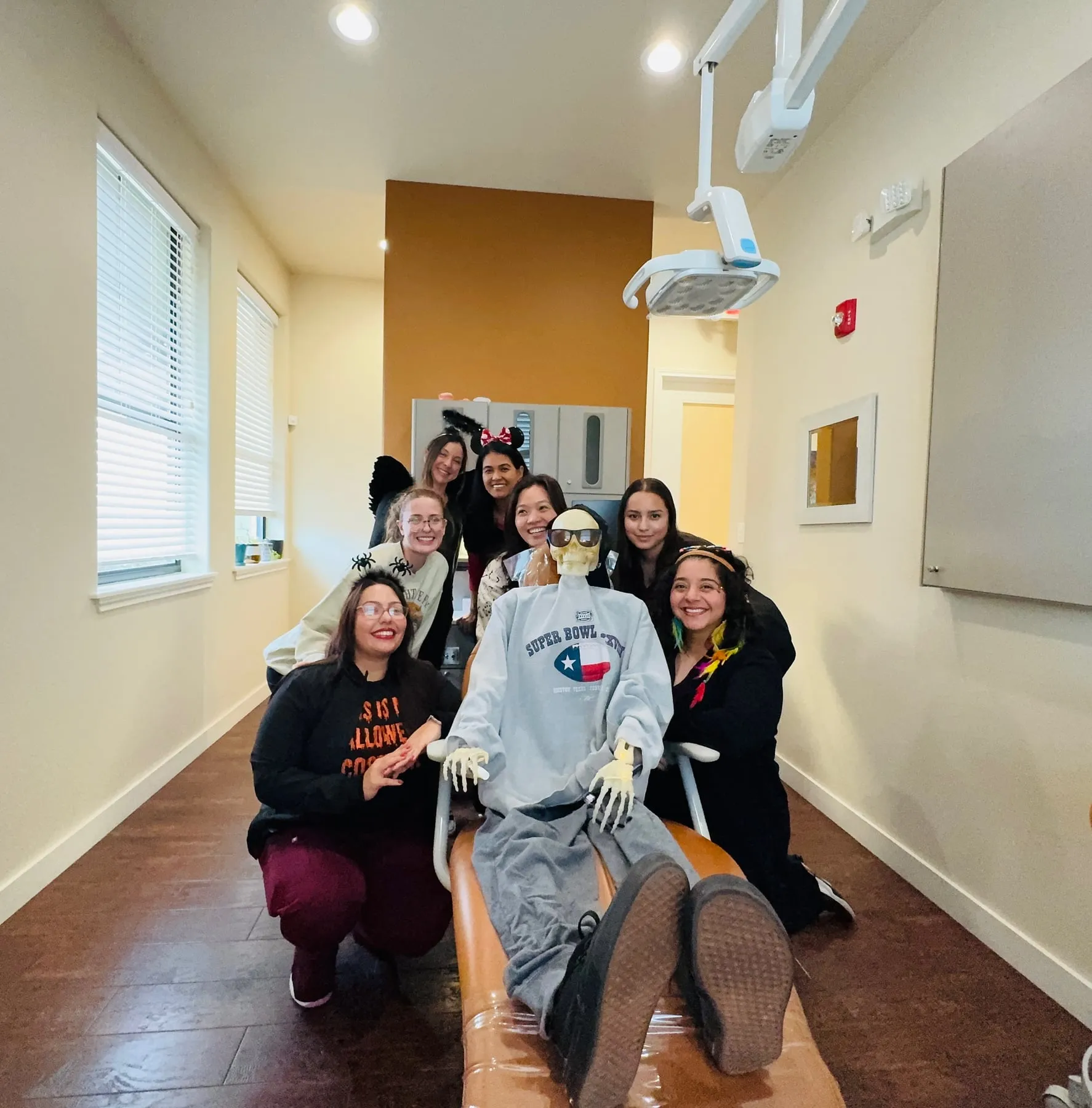 The Hutto Hippo Family Dental team in Halloween costumes gathered around a skeleton patient in the dental chair
