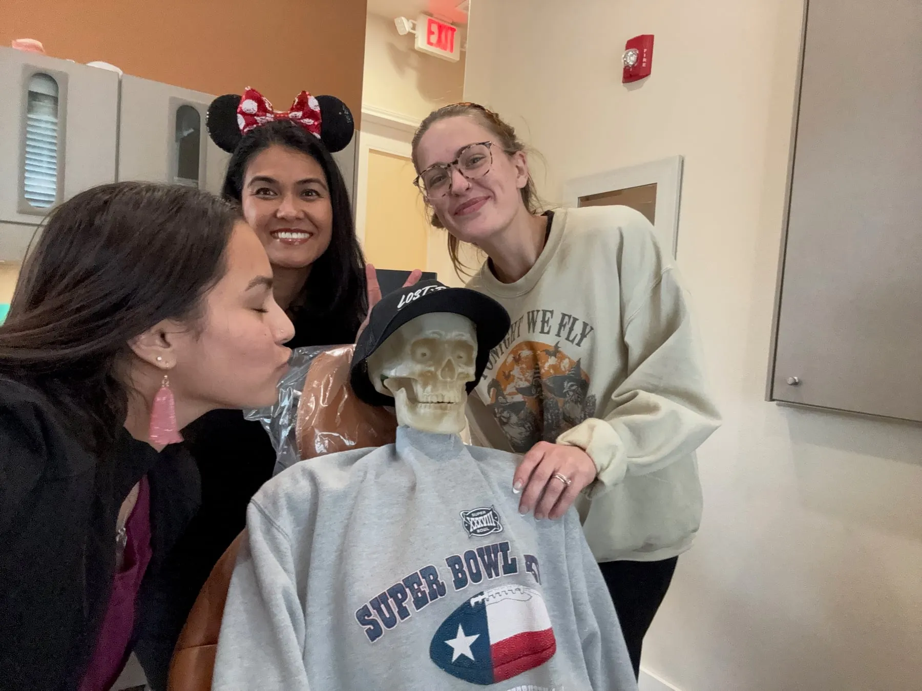Hutto Hippo Family Dental team members posing with the skeleton patient, one giving him a kiss on the cheek