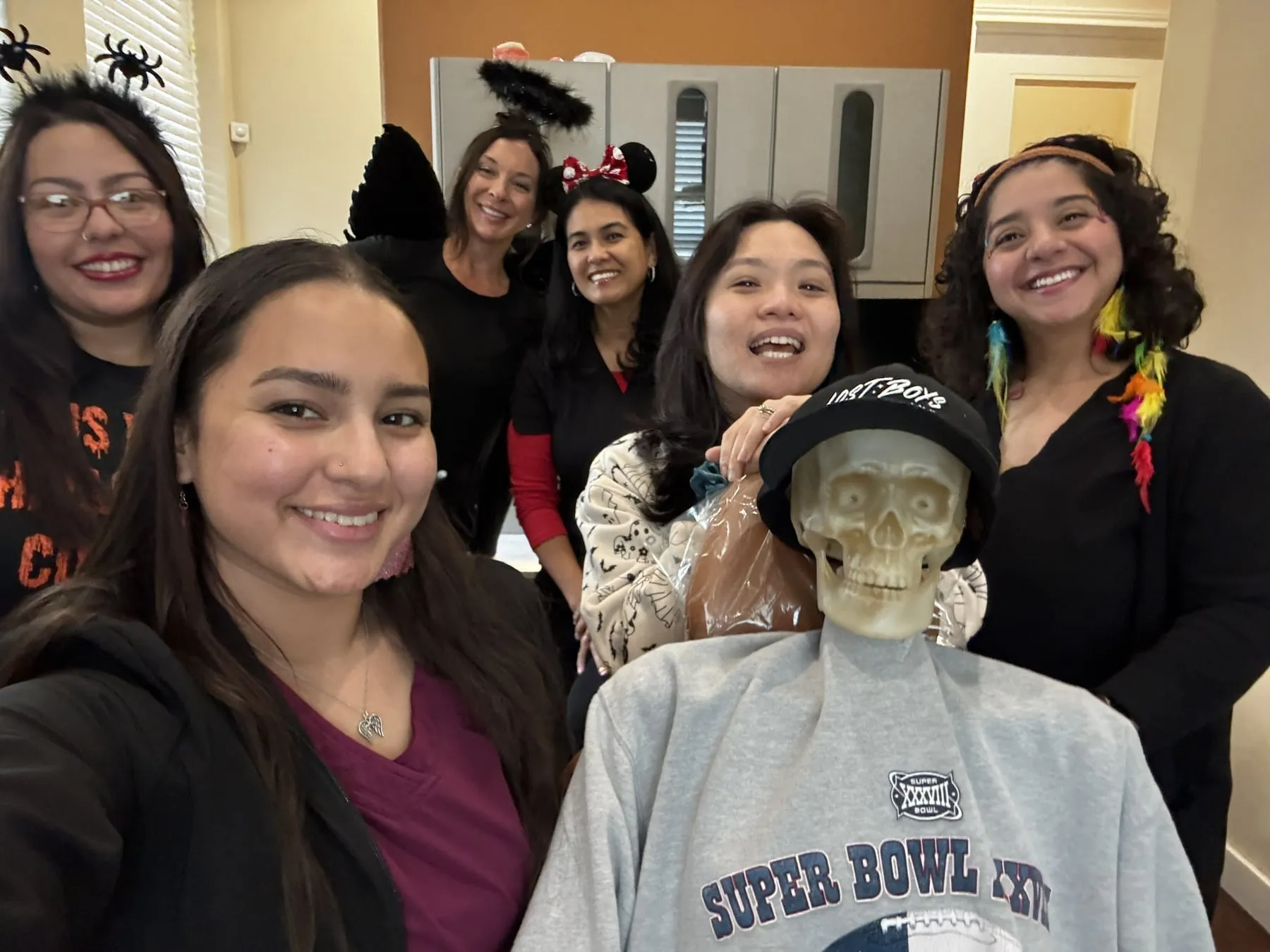 The Hutto Hippo Family Dental team in Halloween costumes taking a group selfie with the skeleton patient